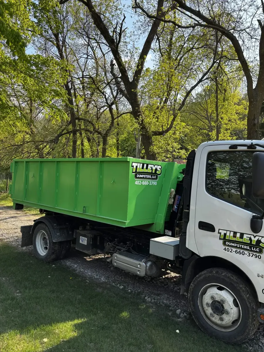 Tilley's roll-off truck delivering a bright green dumpster