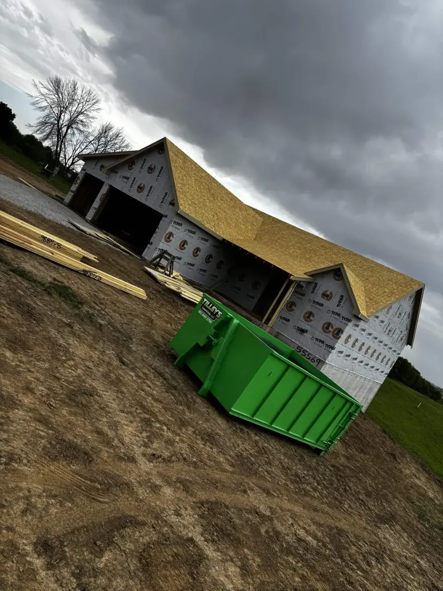 15 yard green Tilley's roll-off dumpster on a job site